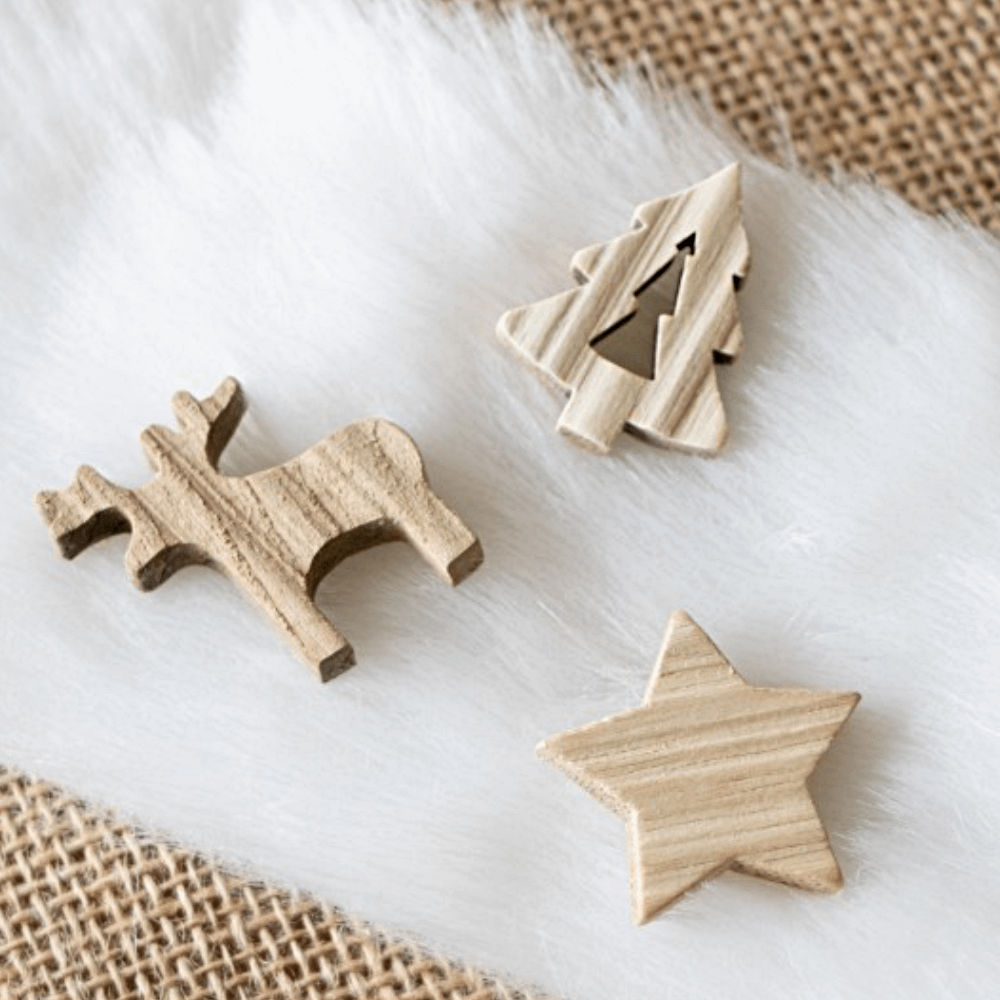 Houten confetti in de vorm van een ster, kerstboom en hert liggen op een witte bonte tafelloper