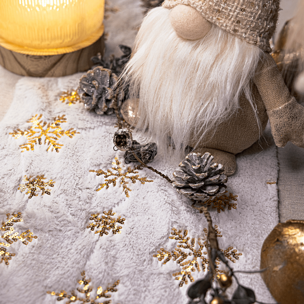 Tafelloper met gouden print versierd met een kerstmannetje en dennenappels met een laagje nepsneeuw erop