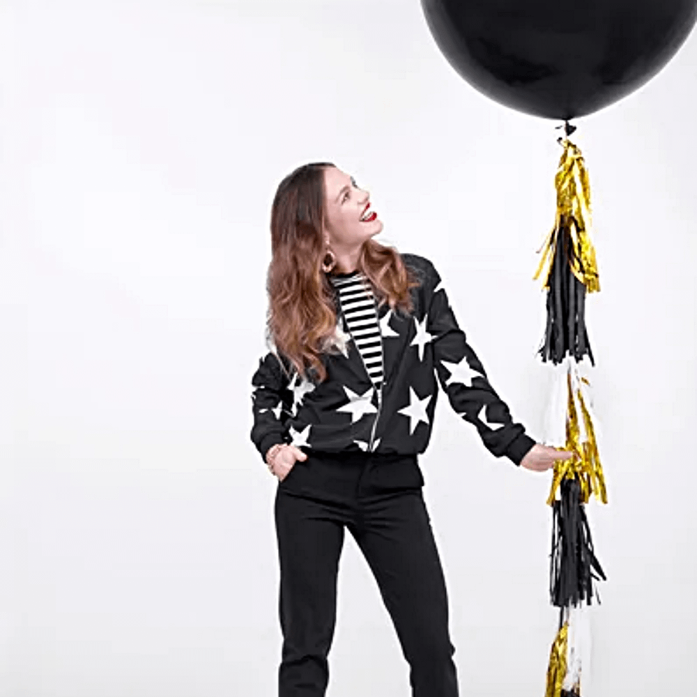 Vrouw houd een grote, zwarte ballon vast aan een tassel lint