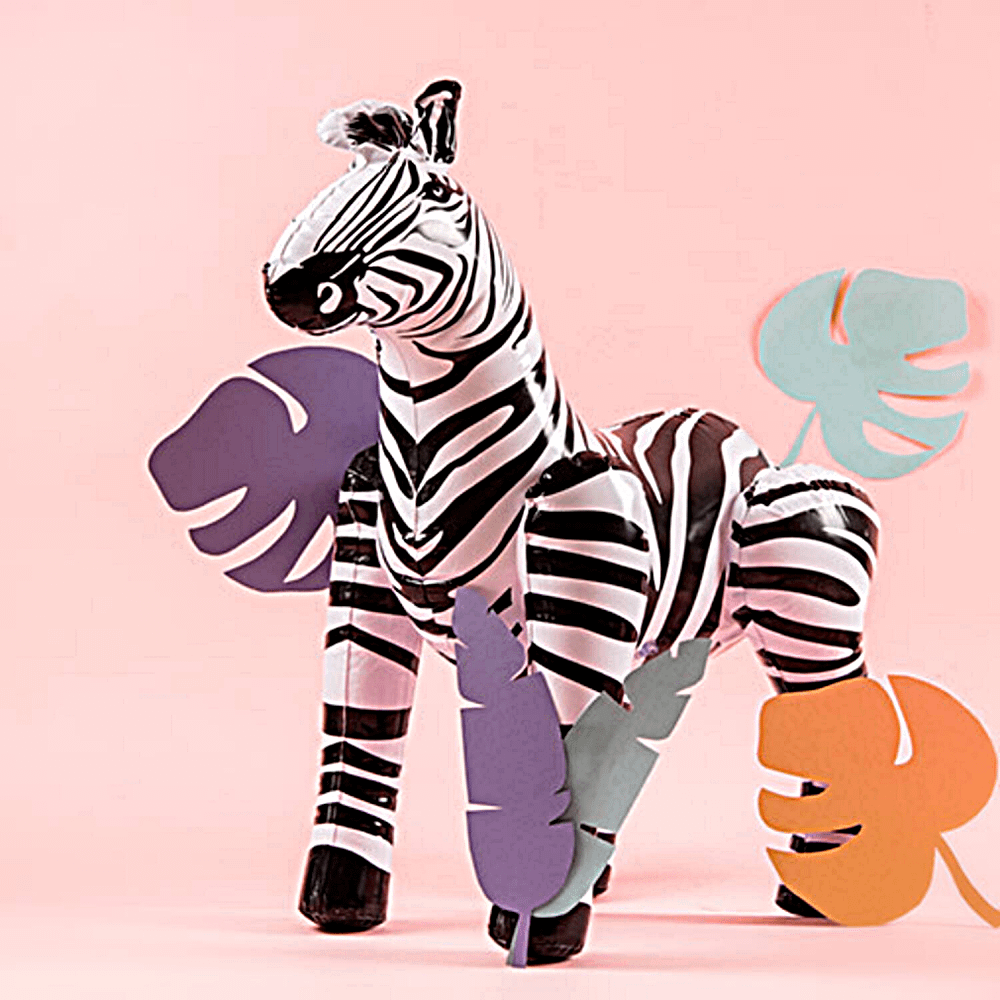 Opblaasbare zebra staat voor een roze achtergrond met palmbladeren