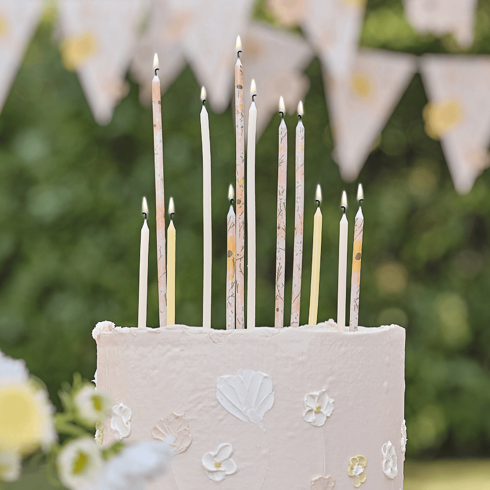 Verjaardagskaarsjes in het perzik, geel en roze met bloemenprint zitten in een bloemen taart