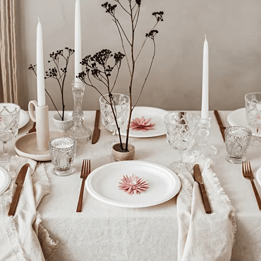 Tafel versierd met goud bestek, witte borden en roze bloemen