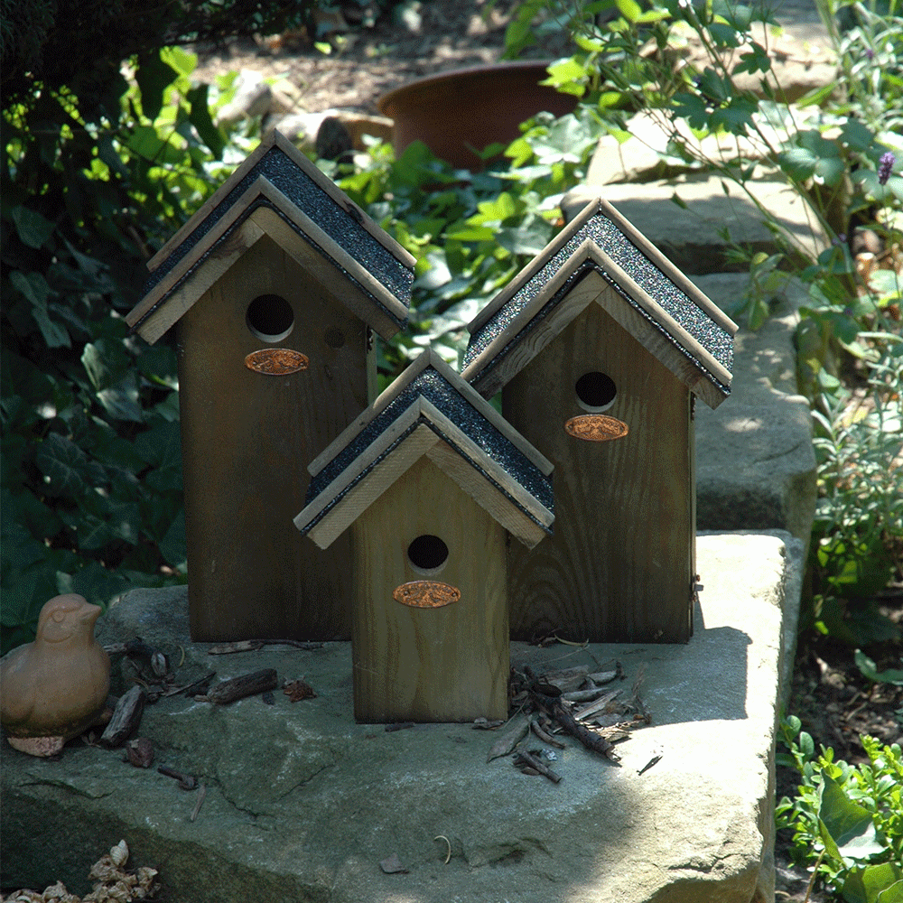 drie vogelhuisjes met bitumen dakje en verschillende afmetingen in tuin
