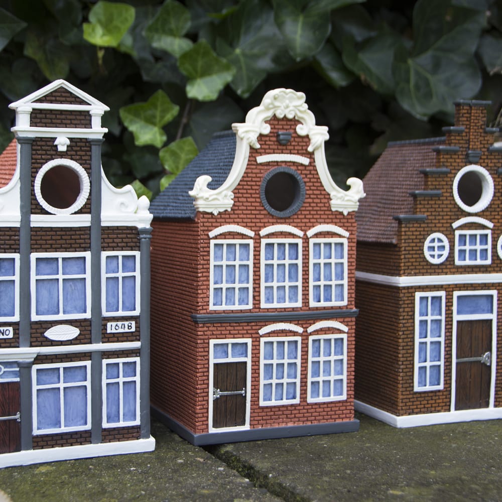Drie vogelhuisjes op een muurtje in de stijl van amsterdamse grachten