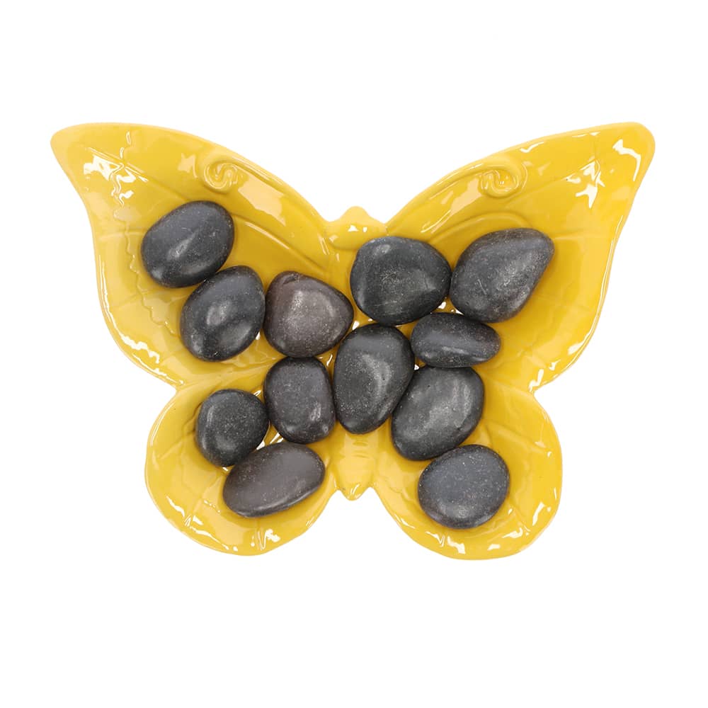 Gele schaal in de vorm van een vlinder met zwarte stenen erop