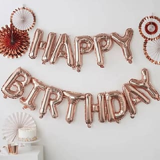 Folieballon in de vorm van de woorden Happy birthday met waaiers tegen de wand