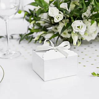 Wit doosje versierd met wit satijnlint staat voor een boeket met witte rozen