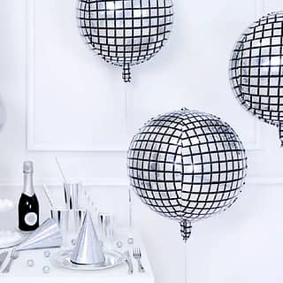 Drie disco folieballonnen met een tafel met zilveren bekers en bordjes