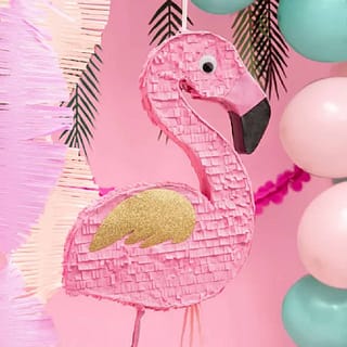 Flamingo pinata op achtergrond van feestversiering zoals ballonnen en palmbladeren