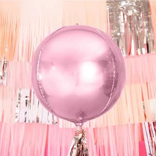 Grote roze ballon met daarachter een roze backdrop