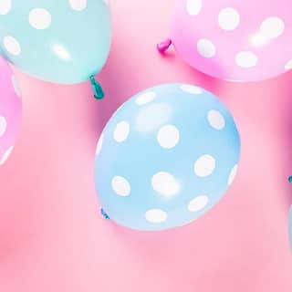 Blauwe en roze ballonnen met witte stippen op een roze achtergrond