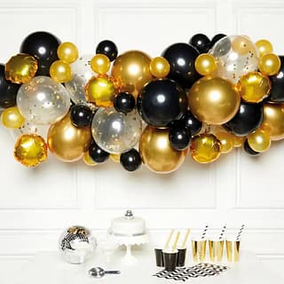 Ballonnenboog met gouden en zwarte ballonnen boven tafel met bekers taart en discobal