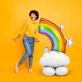 Vrouw met daarnaast een folieballon in de vorm van een wolk met een regenboog erop