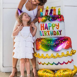 Moeder en kind naast grote folieballon in de vorm van een taart