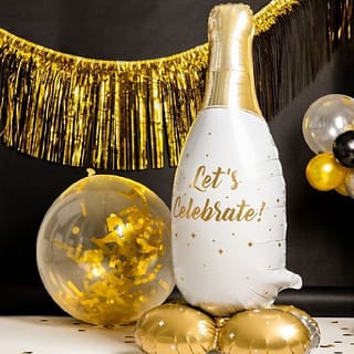 Zwarte achtergrond met gouden slinger, een gouden confettiballon en een folieballon in de vorm van een champagnefles