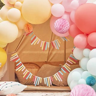 slinger met fringe staafjes in meerdere kleuren op achtergrond van ballonnen
