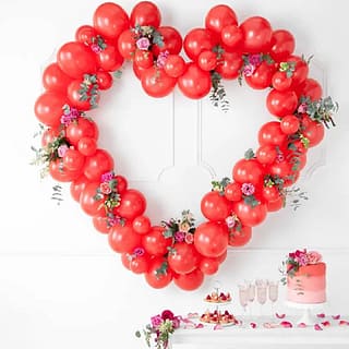Rode ballonnen die samen een hart vormen met daartussen rozen