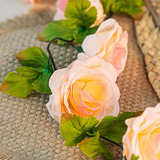 Slinger met roze rozen met een lichtgele binnenkant liggen op een jute placemat op tafel