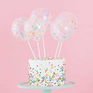 Vijf taart toppers met een ballon eraan in een taart met confetti erop