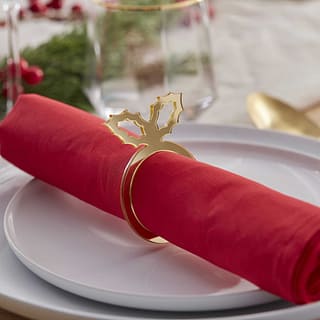 Bordjes met opgerold rood servet met gouden servetring met hulstblaadje
