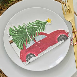 Servet in de vorm van een auto met een kerstboom erop op een bordje