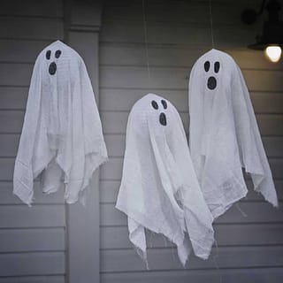 Drie lampionnen met een doek eromheen met spookgezicht erop hangen buiten