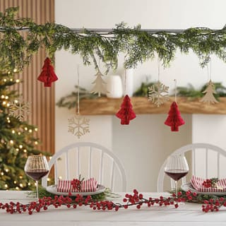 gedekte tafel met tafelstandaard met daaraan groen en kersthangers