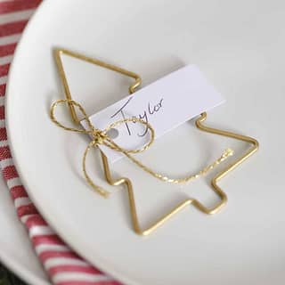 Gouden tafelkaartje in de vorm van een kerstboom op een wit bord