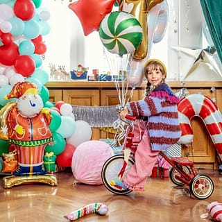 Kind op driewieler omringd door kerstige feestversiering
