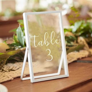 Wit frame met daarop de tekst table 3 op een tafel met groene bladeren