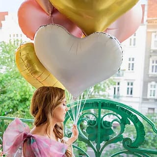 vrouw met bundel met folieballonnen in de vorm van harten