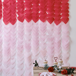 Backdrop met rode en roze hartjes hangt achter een houten tafel met cupcakes en rozen