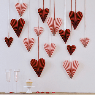 Papieren hartjes in de kleuren roze en rood hangen aan een muur