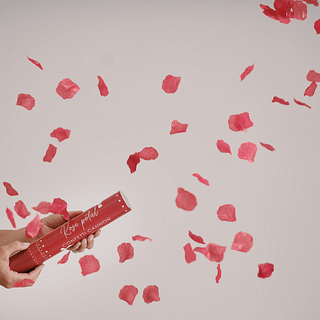 Rode confettishooter schiet rode rozenblaadjes in de lucht