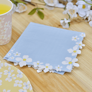 Pastelblauwe servetten met een bloemenrand van madeliefjes op een houten tafel