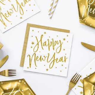 Witte servetten met gouden tekst 'happy new year' op een tafel met gouden bestek en papieren bordjes