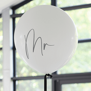 Reuzeballon in het wit met de zwarte tekst 'MR' en een zwart lint hangt voor een raam met zwarte kozijnen