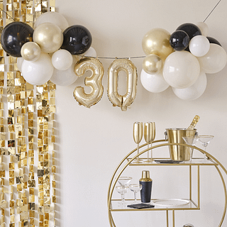 Ballonnenslinger voor 30 jaar hangt boven een gouden cocktailkarretje en voor een gouden backdrop met vierkantjes