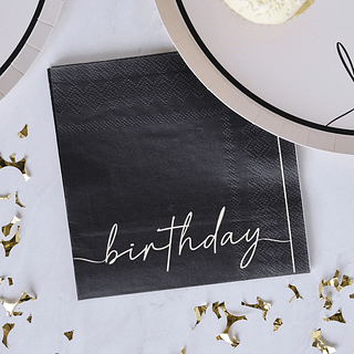 Zwarte servetten met witte tekst birthday ligt op een witte tafel met gouden confetti snippers