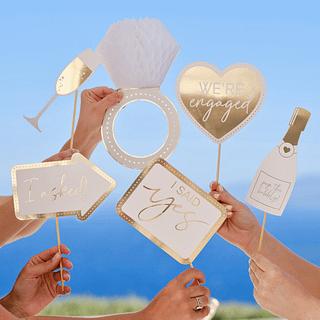 Gouden en witte photobooth props in de vorm van een ring, hartjes, een champagnefles en een champagneglas
