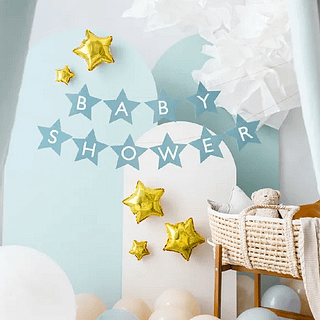 Babykamer met een rieten mandje, een teddybeer, gouden sterren en een lichtblauwe slinger met de witte tekst babyshower