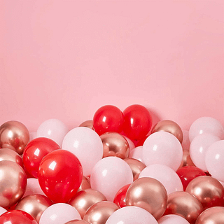 Rode, roze en rose gouden ballonnen liggen op de vloer voor een roze achtergrond