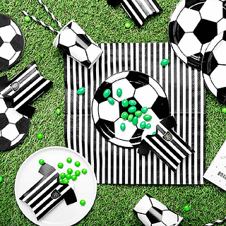 Groen grasveld bedekt met zwart en witte voetbalversiering bestaaned uit bordjes, kartonnen shirts, bekers, servetten en rietjes