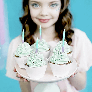 Eng kind staart in je ziel en heeft een bord vast met cupcakes versierd met ombre kaarsen en mintgroene creme