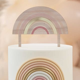 houten taarttopper in de vorm van een regenboog op een taart met een regenboog