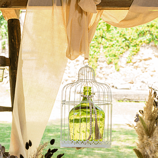 Ivoren drapeerdoek hangt over een houten balk boven een witte vogelkooi