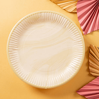 Marmeren bordje in het beige en wit staat op een lichtgele achtergrond met roze, papieren palmbladeren