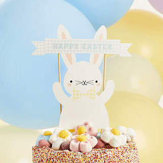 Taart met gekleurde spikkels en snoepjes is versierd met een konijntje met een gele strik
