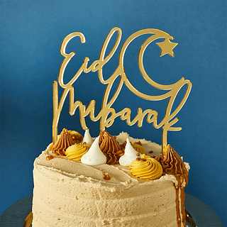 Gouden taart topper met de tekst eid mubarak zit in een taart voor een donkerblauwe achtergrond
