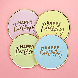 Bordjes in pasteltinten roze, geel, groen en blauw met een gouden rand en tekst happy birthday op een lichtroze achtergrond